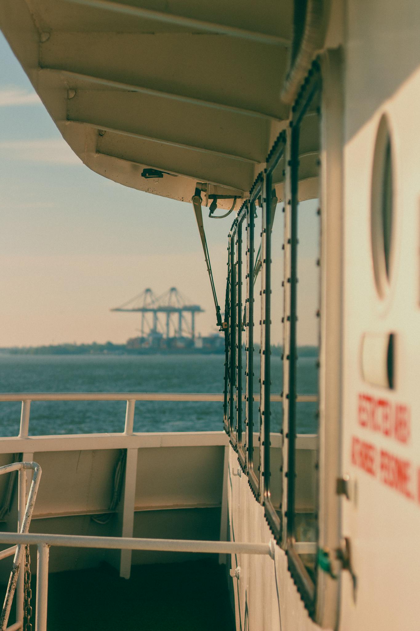 An industrial shipping scene from a passenger ship's deck on a sunny day.